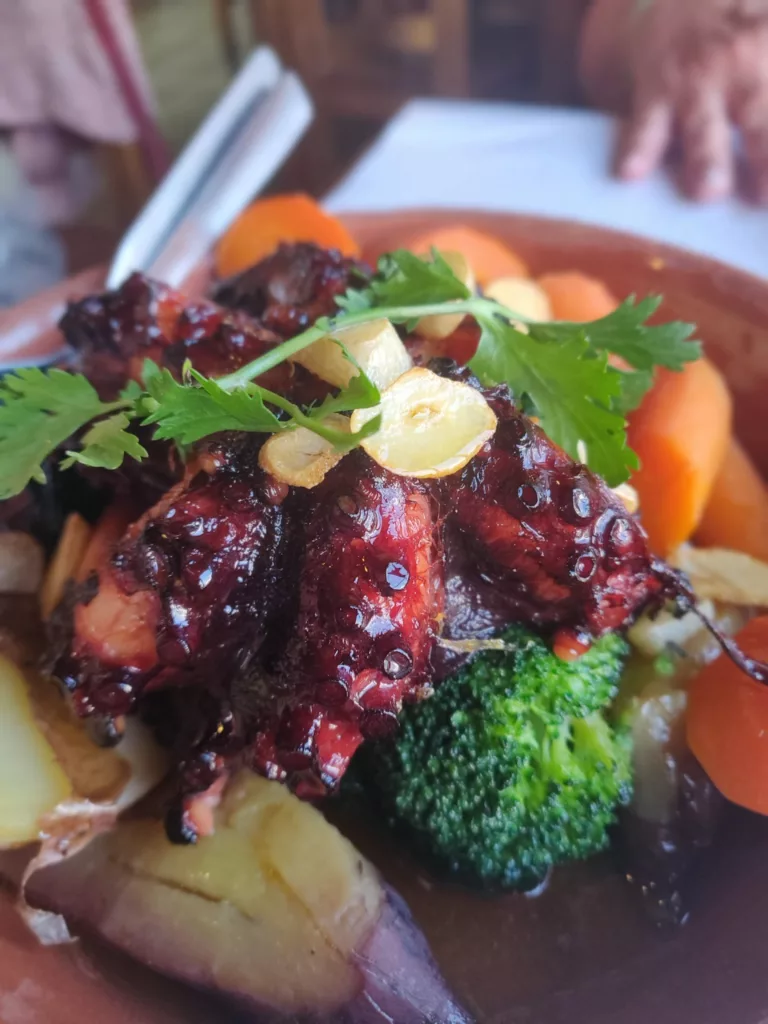 A close-up of a plate of grilled octopus served with fresh vegetables, showcasing traditional Portuguese cuisine and locally sourced ingredients.